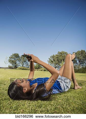 Stock Photograph - Mixed race girl using cell phone in park. Fotosearch