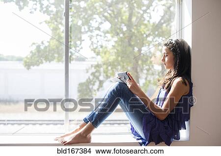 Mixed race girl using digital tablet at window View Large Photo Image Picture - Mixed race girl using digital tablet at window. Fotosearch