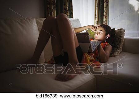 Stock Photo - Mixed race girl using digital tablet on sofa. Fotosearch