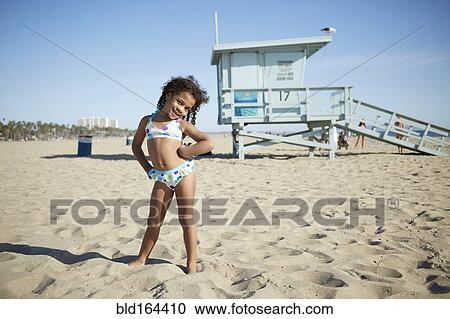Stock Image - Mixed race girl wearing bikini on beach. Fotosearch