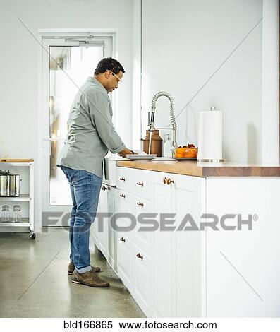 Mixed race man washing dishes in kitchen View Large Photo Image Stock Photography - Mixed race man washing dishes in kitchen. Fotosearch