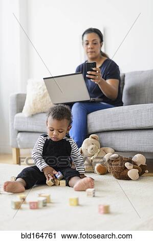 Mixed race mother and baby son relaxing in living room View Large Photo Image Stock Image - Mixed race mother and baby son relaxing in living room. Fotosearch