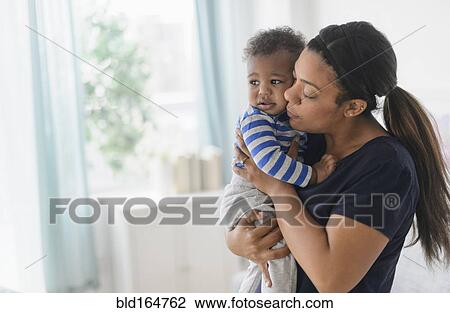 Mixed race mother comforting upset baby son View Large Photo Image Stock Image - Mixed race mother comforting upset baby son. Fotosearch