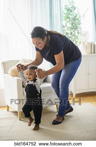 Mixed race mother helping baby son walk in living room View Large Photo Image Stock Image - Mixed race mother helping baby son walk in living room. Fotosearch