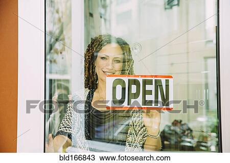 Stock Image - Mixed race store owner opening door. Fotosearch