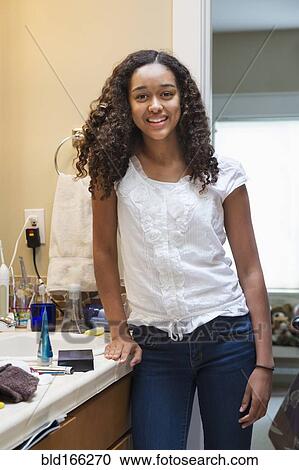 Stock Image - Mixed race teenage girl smiling in bathroom. Fotosearch