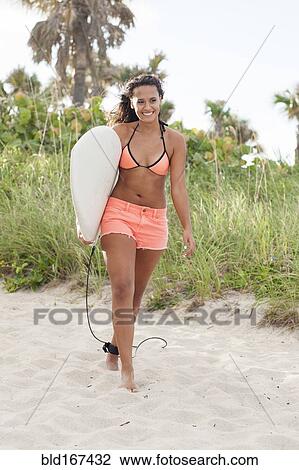 Mixed race woman carrying surfboard on beach View Large Photo Image Stock Image - Mixed race woman carrying surfboard on beach. Fotosearch