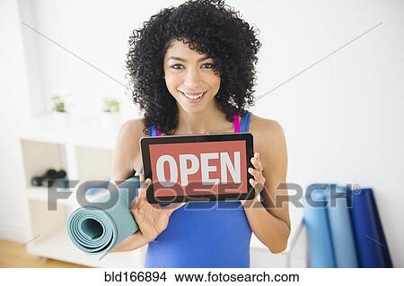 Picture - Mixed race woman holding open sign in yoga studio. Fotosearch