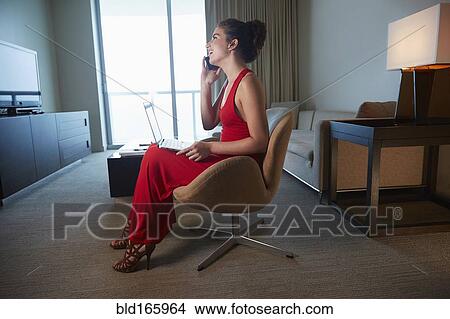 Mixed race woman in evening gown using laptop and cell phone View Large Photo Image Picture - Mixed race woman in evening gown using laptop and cell phone. Fotosearch