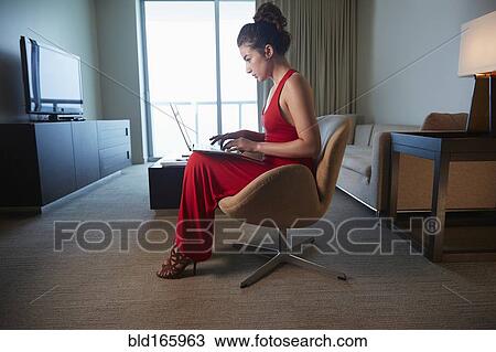 Stock Image - Mixed race woman in evening gown using laptop. Fotosearch