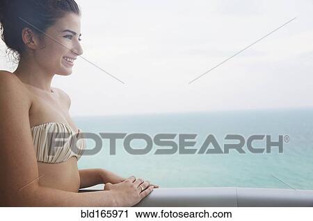 Stock Image - Mixed race woman overlooking ocean from balcony. Fotosearch