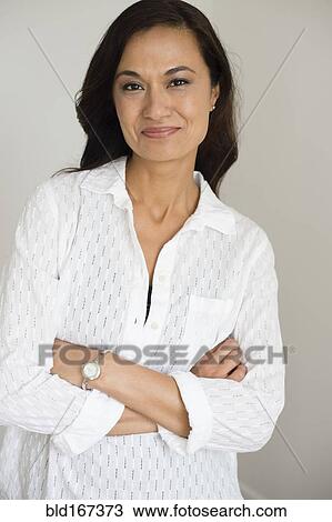 Stock Image - Mixed race woman smiling with arms crossed. Fotosearch