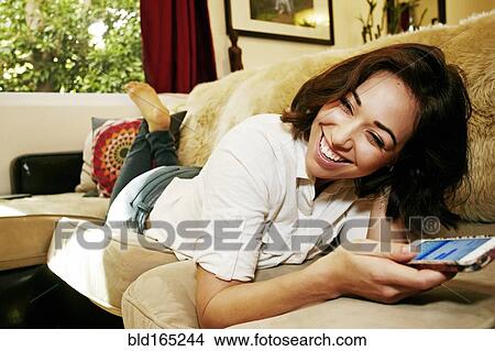 Mixed race woman using cell phone on sofa View Large Photo Image Picture - Mixed race woman using cell phone on sofa. Fotosearch