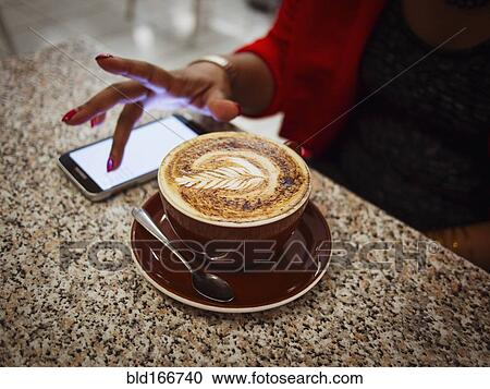 Mixed race woman using cell phone with coffee in cafe View Large Photo Image Stock Image - Mixed race woman using cell phone with coffee in cafe. Fotosearch