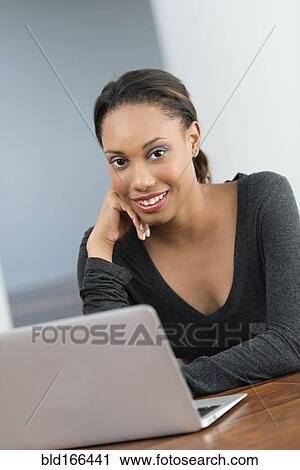 Mixed race woman using laptop at desk View Large Photo Image Stock Image - Mixed race woman using laptop at desk. Fotosearch