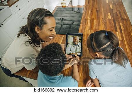 Mother and children video chatting with father in kitchen View Large Photo Image Stock Image - Mother and children video chatting with father in kitchen. Fotosearch