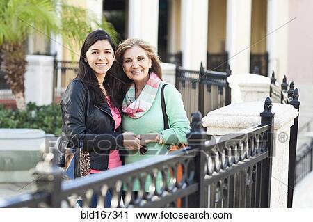 Stock Image - Mother and daughter hugging at gate. Fotosearch