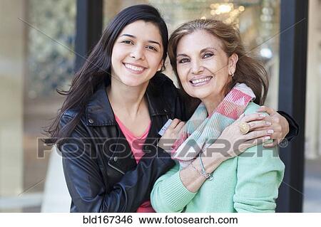 Stock Photograph - Mother and daughter hugging outside store. Fotosearch