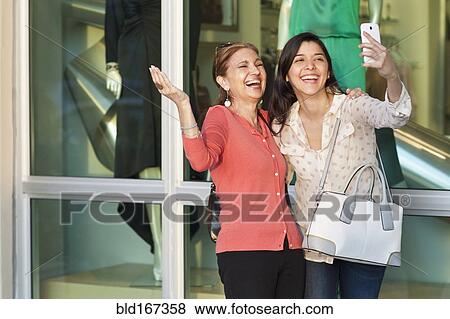 Stock Photo - Mother and daughter taking selfie outside store. Fotosearch