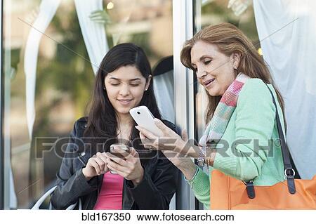 Mother and daughter using cell phones outdoors View Large Photo Image Stock Image - Mother and daughter using cell phones outdoors. Fotosearch