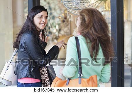 Stock Photography - Mother and daughter window shopping on sidewalk. Fotosearch