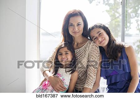 Stock Photo - Mother and daughters hugging at window. Fotosearch