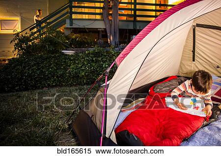 Stock Photography - Mother watching Mixed race son coloring in backyard tent. Fotosearch