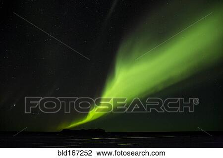 Stock Image - Northern Lights glowing green in night sky. Fotosearch