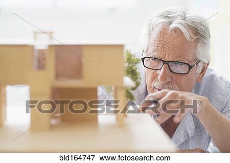 Stock Photo - Older Caucasian architect building scale model in office. Fotosearch