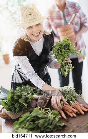Stock Image - Older Caucasian couple harvesting vegetables from garden. Fotosearch
