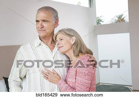 Stock Photo - Older Caucasian couple hugging in living room. Fotosearch