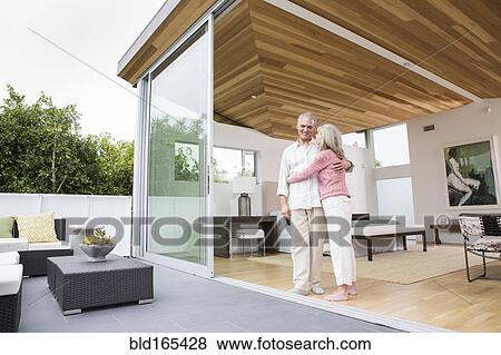 Stock Photo - Older Caucasian couple hugging on porch. Fotosearch