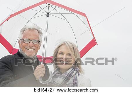 Older Caucasian couple standing under umbrella View Large Photo Image Stock Photo - Older Caucasian couple standing under umbrella. Fotosearch