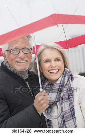 Older Caucasian couple standing under umbrella View Large Photo Image Stock Photo - Older Caucasian couple standing under umbrella. Fotosearch