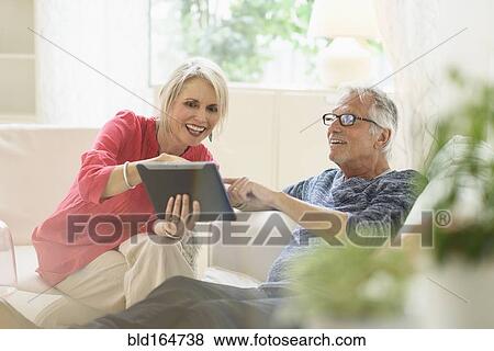 Older Caucasian couple using digital tablet in living room View Large Photo Image Stock Photo - Older Caucasian couple using digital tablet in living room. Fotosearch