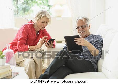 Stock Photo - Older Caucasian couple using technology in living room. Fotosearch
