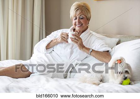 Older Caucasian woman and dog relaxing on bed View Large Photo Image Stock Image - Older Caucasian woman and dog relaxing on bed. Fotosearch