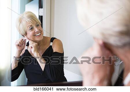Older Caucasian woman attaching earring in mirror View Large Photo Image Stock Image - Older Caucasian woman attaching earring in mirror. Fotosearch