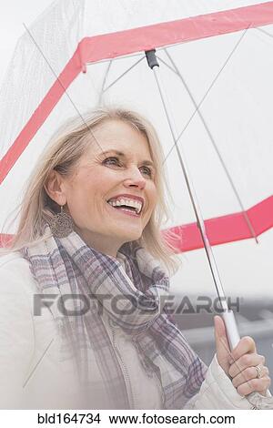 Older Caucasian woman standing under umbrella View Large Photo Image Picture - Older Caucasian woman standing under umbrella. Fotosearch