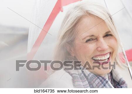 Stock Photography - Older Caucasian woman standing under umbrella. Fotosearch