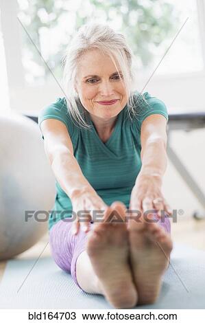 Stock Image - Older Caucasian woman stretching in gym. Fotosearch