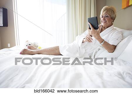 Older Caucasian woman using digital tablet on bed View Large Photo Image Stock Image - Older Caucasian woman using digital tablet on bed. Fotosearch