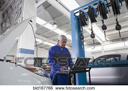 Older Hispanic mechanic using laptop in garage View Large Photo Image Stock Photograph - Older Hispanic mechanic using laptop in garage. Fotosearch