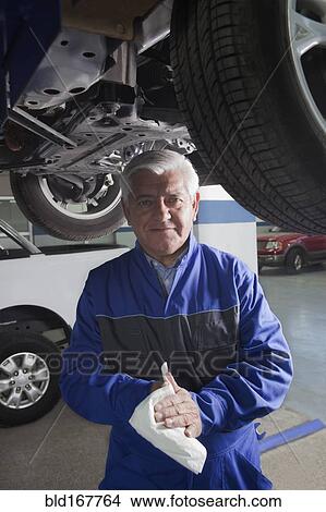Picture - Older Hispanic mechanic working in garage. Fotosearch