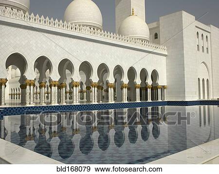 Stock Photo - Ornate colonnade reflecting in still pool, Abu Dhabi, Abu Dhabi Emirate, United Arab Emirates. Fotosearch