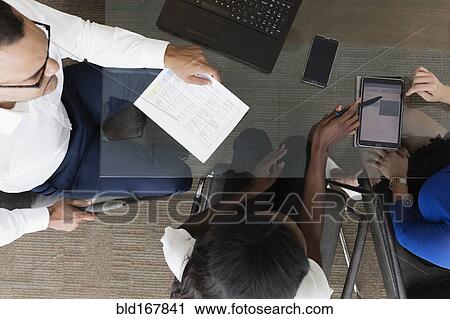 Stock Image - Overhead view of business people talking in office meeting. Fotosearch