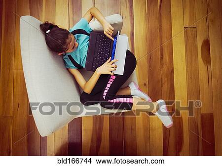 Picture - Overhead view of mixed race girl using digital tablet in armchair. Fotosearch