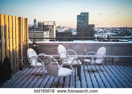 Stock Photo - Patio furniture in snow on urban rooftop, New York, New York, United States. Fotosearch