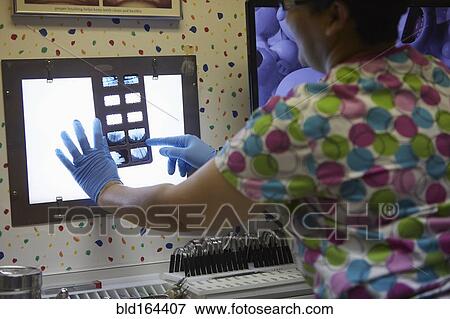 Stock Photo - Pediatric dentist examining x-rays in office. Fotosearch