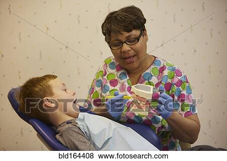 Pediatric dentist showing model teeth to patient in office View Large Photo Image Stock Photo - Pediatric dentist showing model teeth to patient in office. Fotosearch